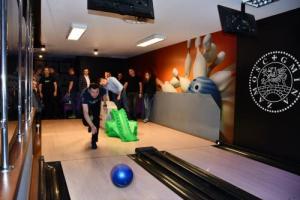 Zdjęcie wykonane z przodu, podczas zmagań w trakcie turnieju bowlingowego. Na zdjęciu uczestnicy zawodów podczas zmagań reprezentacji jednostek penitencjarnych na torach. Pierwszy z lewej zawodnik, który zajął trzecie miejsce w kategorii mężczyzn.
