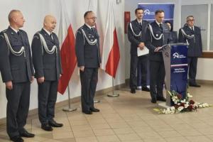 Zdjęcie przedstawia umundurowanych funkcjonariuszy w czasie uroczystości z okazji Święta Niepodległości. W tle widoczny roll up z napisem Zakład Karny w Hrubieszowie. Zdjęcie wykonano w czasie przemówienia Dyrektora jednostki na sali widzeń Zakładu Karnego w Hrubieszowie. 
