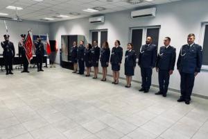 Odznaczeni oraz awansowani funkcjonariusze Zakładu Karnego w Zarębie stoją w szeregu ubrani w niebieskie mundury. Po prawej stronie stoi trzech funkcjonariuszy ze sztandarem.
