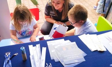 Funkcjonariuszka Służby Więziennej rysuje z dziećmi siedzącymi przy stoliku