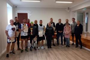 Na zdjęciu kilkanaście osób, wśród których znajdują się uczestnicy, w tym zwycięzcy biegu, oraz przedstawiciele organizatora wydarzenia.
