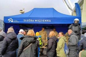 Stoisko promocyjne Służby Więziennej wraz z funkcjonariuszami i odwiedzającymi.

